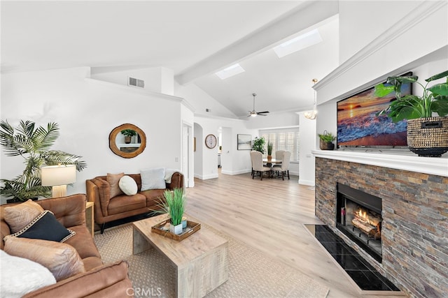 living room featuring light wood-type flooring, vaulted ceiling with beams, ceiling fan, and a fireplace