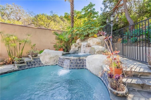 view of swimming pool with pool water feature and an in ground hot tub