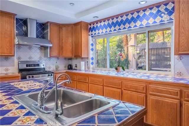 kitchen with decorative backsplash, sink, wall chimney exhaust hood, and stainless steel range with gas stovetop