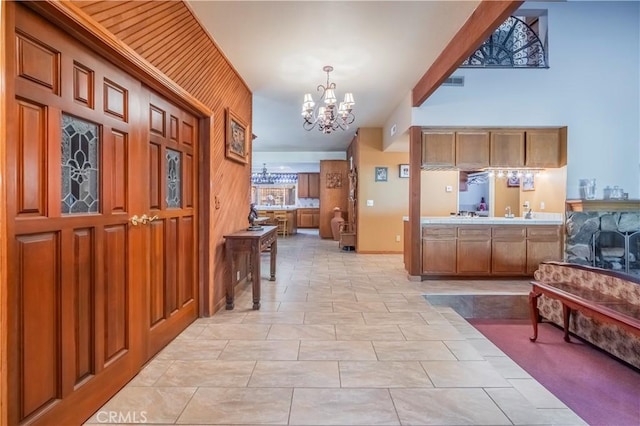 interior space with a chandelier, pendant lighting, wood walls, and light tile patterned flooring