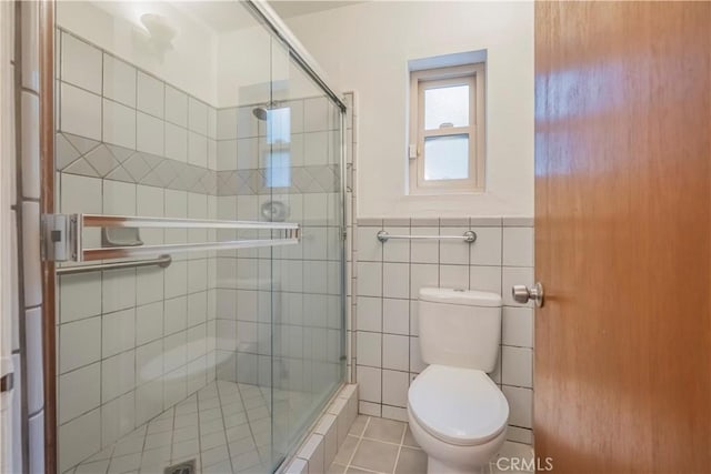 bathroom with tile patterned floors, tile walls, and an enclosed shower