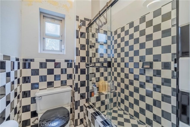 bathroom with tiled shower, toilet, and tile walls