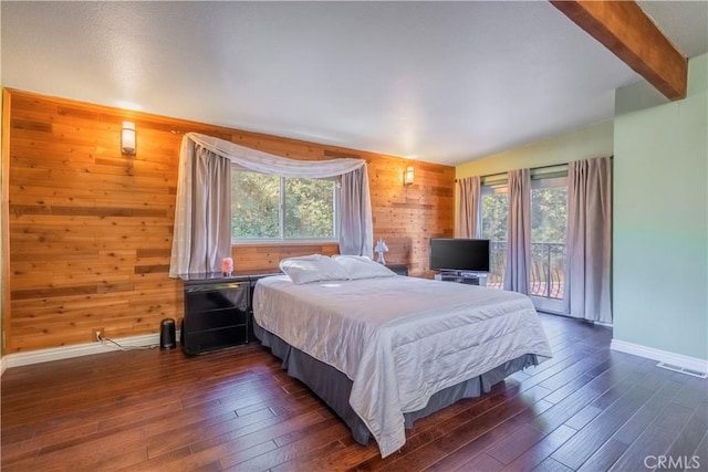 bedroom featuring multiple windows, wooden walls, dark hardwood / wood-style floors, and access to exterior