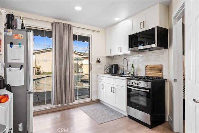 kitchen with white cabinets, stainless steel appliances, light hardwood / wood-style floors, and sink