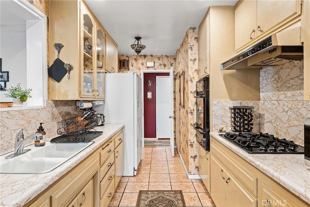 kitchen featuring sink, tasteful backsplash, light brown cabinetry, light tile patterned flooring, and black appliances