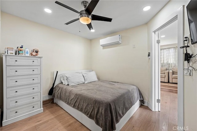 bedroom featuring ceiling fan, light hardwood / wood-style floors, and an AC wall unit