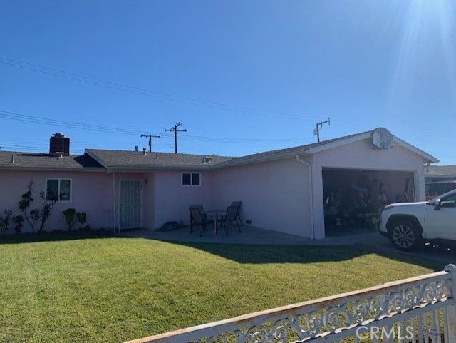 rear view of house with a lawn, a patio, and a garage