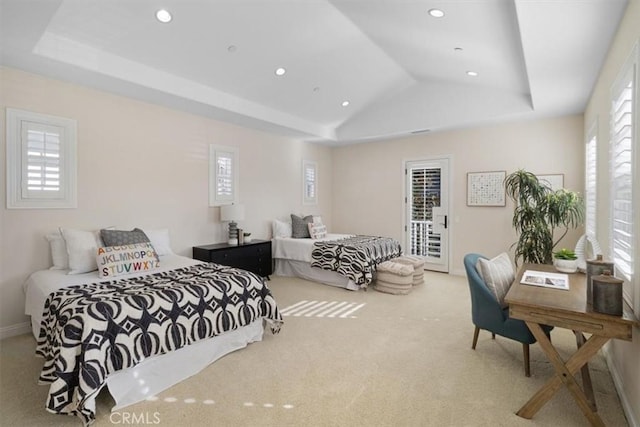 bedroom featuring access to exterior, carpet flooring, a raised ceiling, and multiple windows