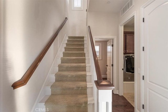 staircase featuring hardwood / wood-style floors, a healthy amount of sunlight, and washer / dryer