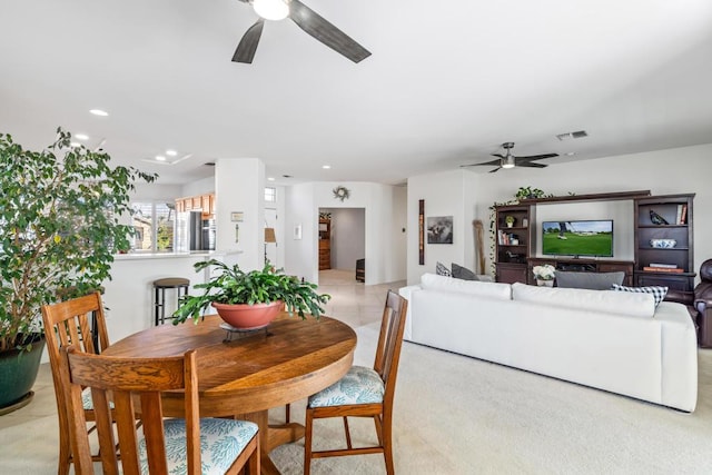 dining area with ceiling fan and light colored carpet