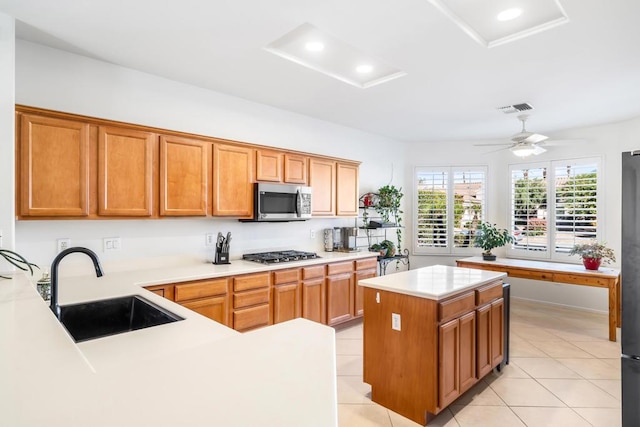 kitchen with appliances with stainless steel finishes, ceiling fan, sink, light tile patterned floors, and a kitchen island