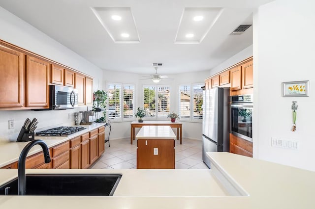 kitchen with ceiling fan, a center island, sink, stainless steel appliances, and light tile patterned floors