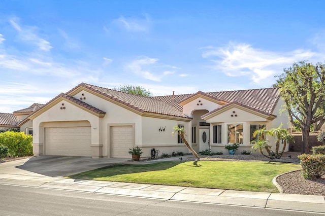 mediterranean / spanish-style house featuring a garage and a front lawn