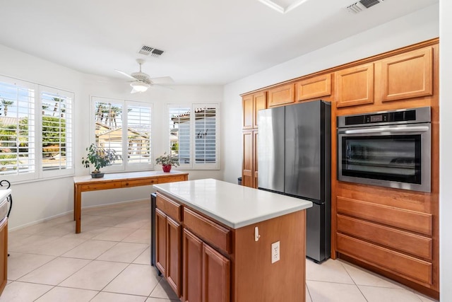 kitchen featuring ceiling fan, a kitchen island, stainless steel appliances, and light tile patterned floors