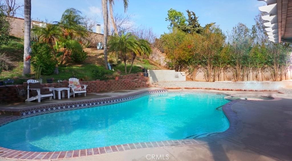 view of pool featuring a patio, a pool with connected hot tub, and fence