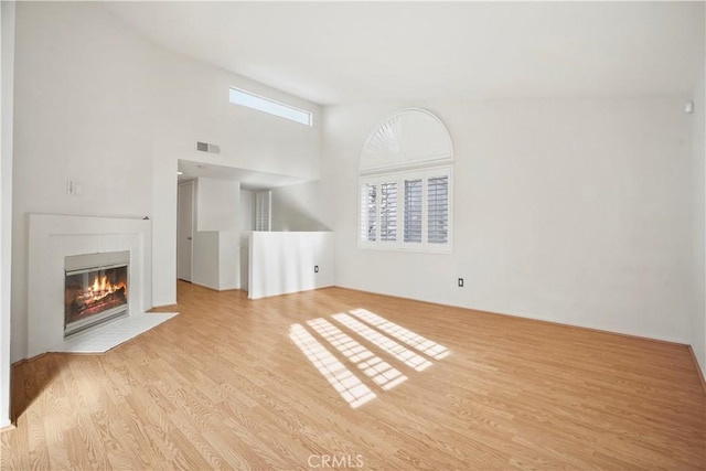 unfurnished living room with a high ceiling and light hardwood / wood-style floors