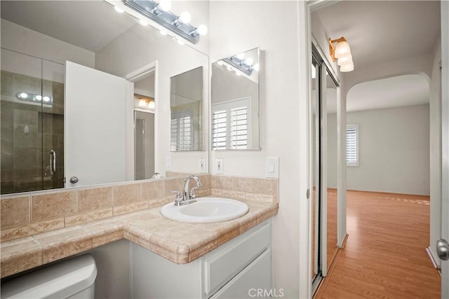 bathroom with toilet, a shower with door, vanity, and hardwood / wood-style flooring