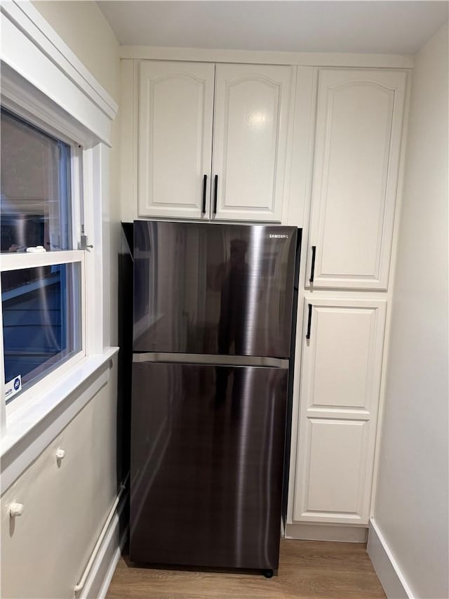 kitchen with white cabinetry, refrigerator, and light wood-type flooring