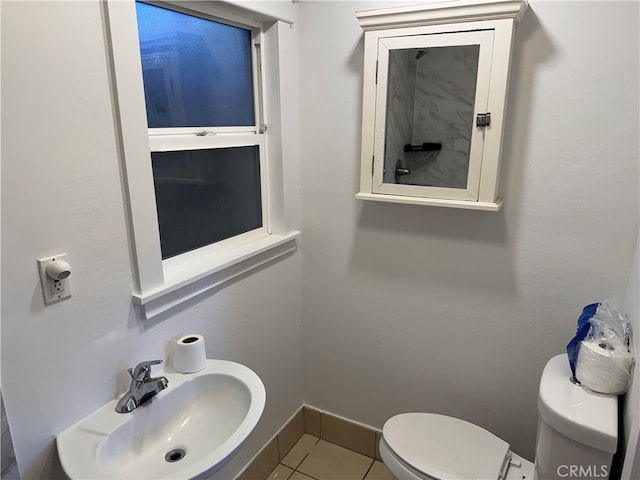 bathroom with toilet, sink, and tile patterned flooring