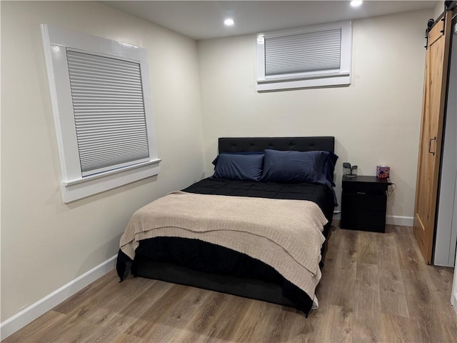 bedroom featuring a barn door and hardwood / wood-style flooring