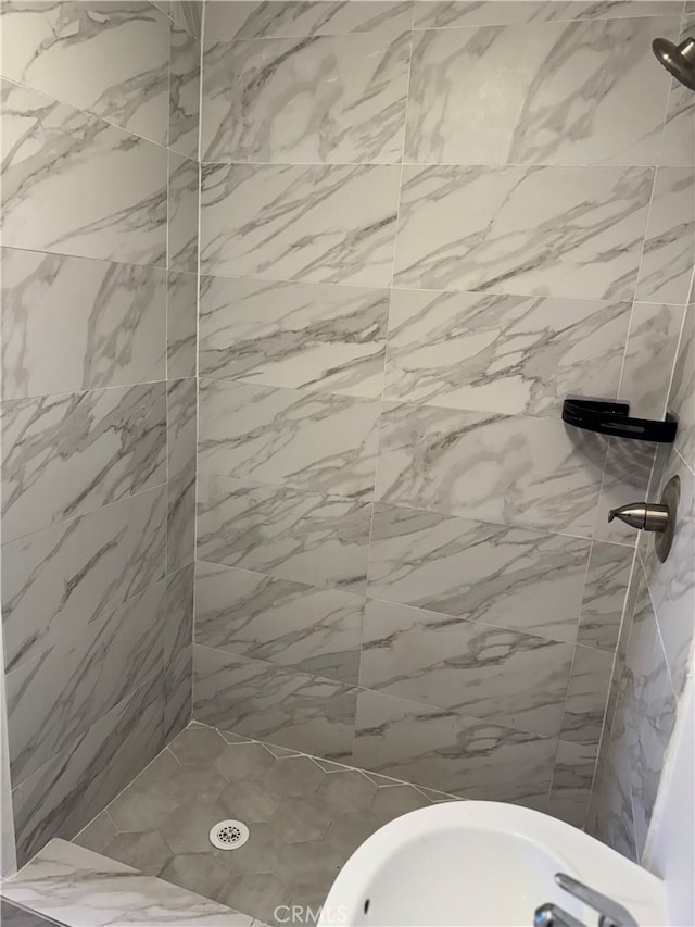 bathroom featuring a tile shower and sink