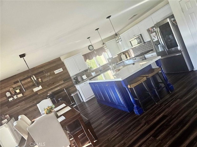 kitchen featuring a center island, hanging light fixtures, appliances with stainless steel finishes, tasteful backsplash, and white cabinetry