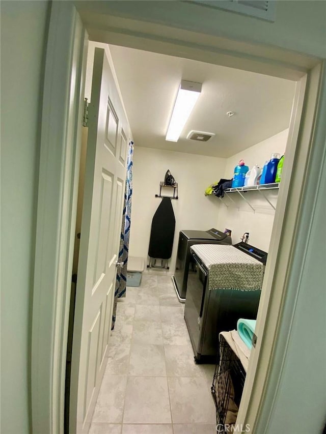 clothes washing area featuring washer and clothes dryer and light tile patterned floors