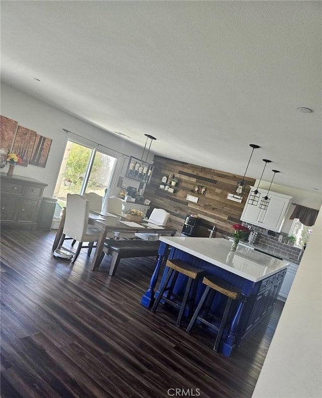 dining space featuring dark wood-type flooring and wooden walls