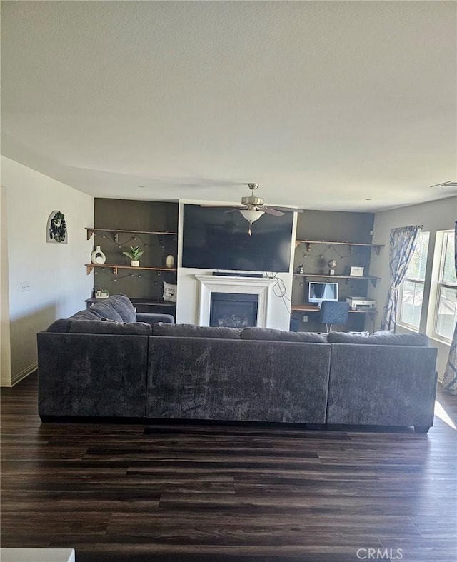 living room with ceiling fan and dark wood-type flooring