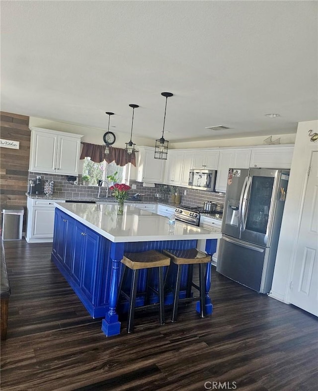 kitchen with white cabinetry, a center island, blue cabinets, pendant lighting, and appliances with stainless steel finishes