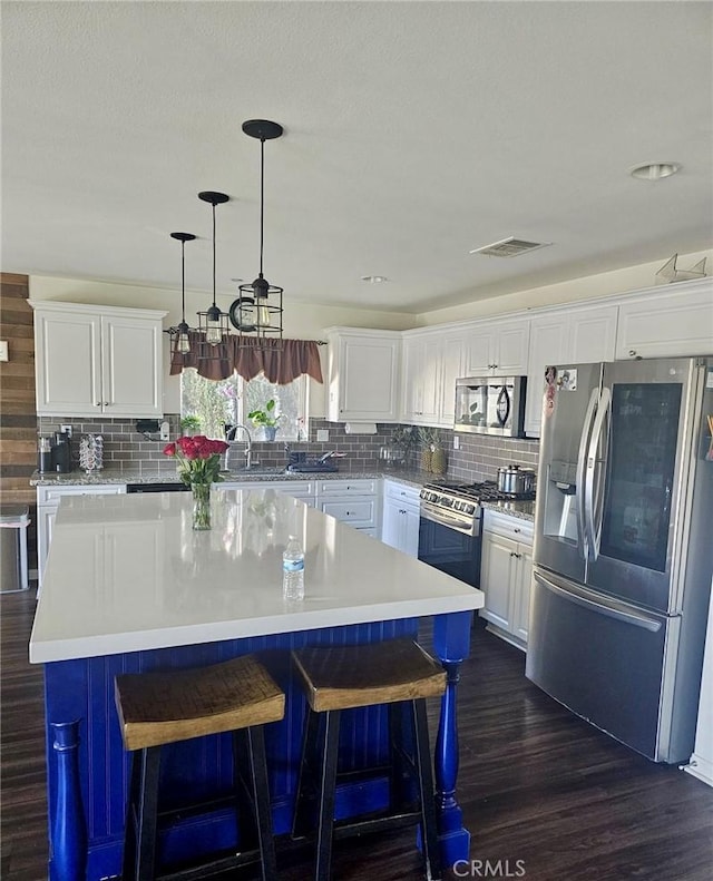 kitchen featuring a kitchen island, white cabinetry, dark wood-type flooring, and appliances with stainless steel finishes