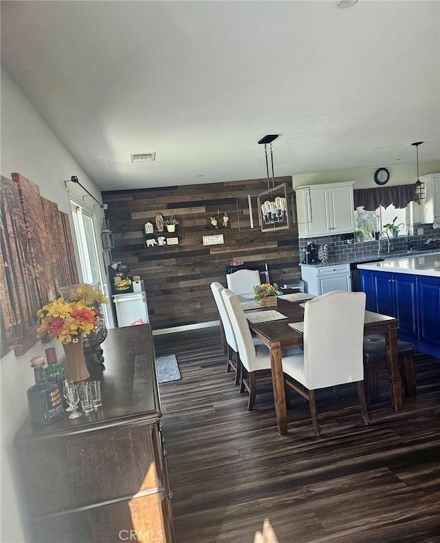 dining area featuring dark hardwood / wood-style flooring and wooden walls