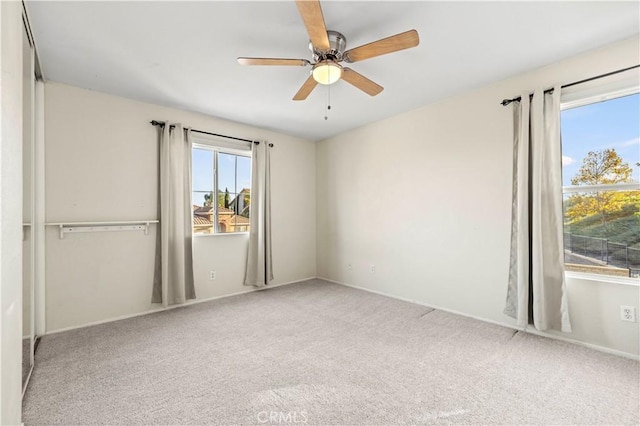 spare room with ceiling fan and light carpet