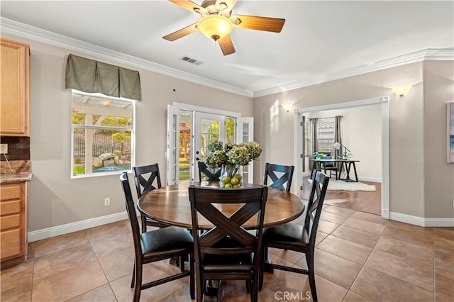 tiled dining room with plenty of natural light, ceiling fan, crown molding, and french doors