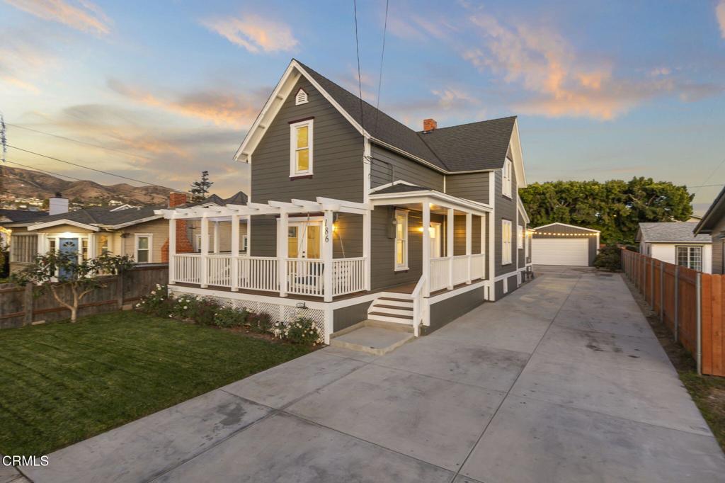 view of front of home with a lawn, a pergola, an outdoor structure, a garage, and a porch