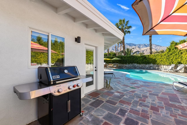 view of pool featuring a mountain view, a patio, and area for grilling