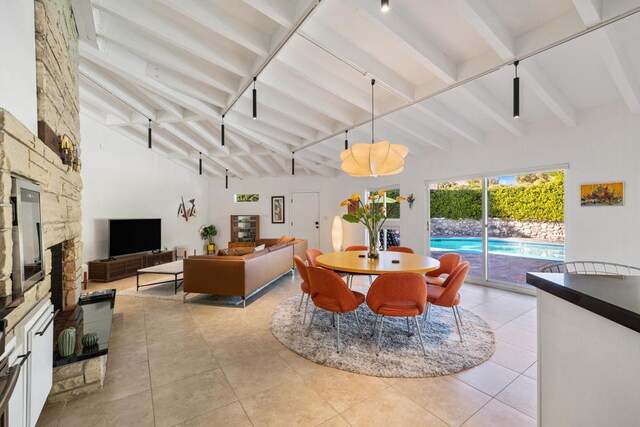 tiled dining room with beamed ceiling and a stone fireplace