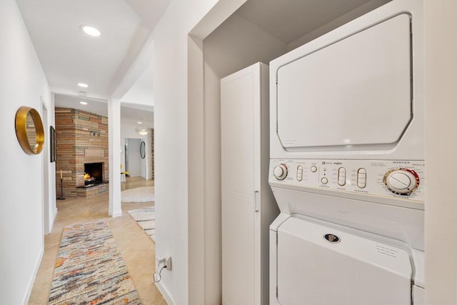 washroom with a tiled fireplace, stacked washer and clothes dryer, and light tile patterned flooring