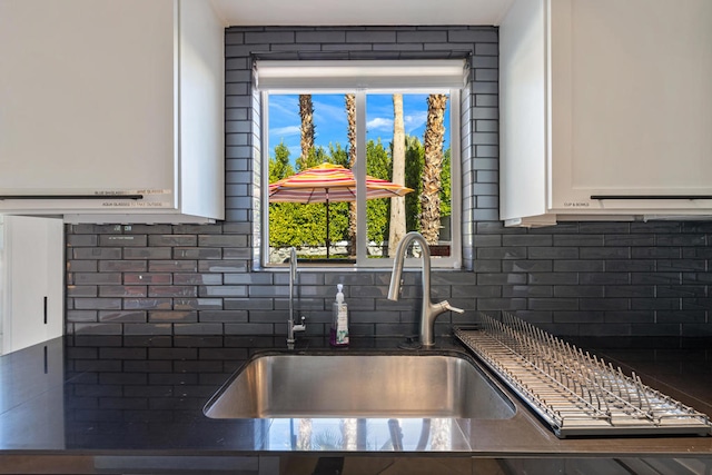 details featuring sink, white cabinets, and tasteful backsplash