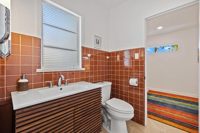 bathroom featuring tile patterned flooring, vanity, tile walls, and toilet