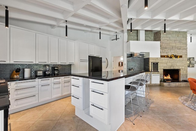 kitchen with light tile patterned flooring, black refrigerator, white cabinets, and tasteful backsplash