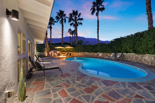 pool at dusk featuring a patio area and a mountain view