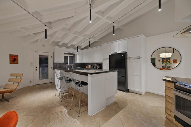 kitchen with white cabinets, a kitchen bar, tasteful backsplash, black fridge, and stainless steel electric range