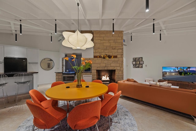 dining area featuring beamed ceiling and a stone fireplace