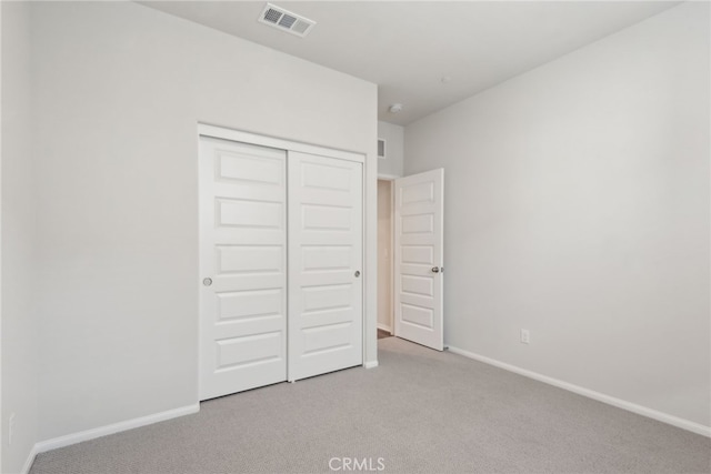 unfurnished bedroom with light carpet, baseboards, visible vents, and a closet