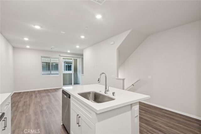 kitchen featuring light countertops, stainless steel dishwasher, white cabinets, a sink, and an island with sink