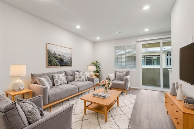 living room with light wood-type flooring, visible vents, and recessed lighting