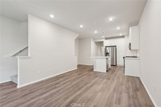 unfurnished living room featuring recessed lighting, baseboards, light wood finished floors, and stairs