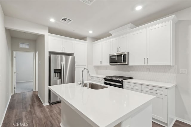 kitchen featuring white cabinets, a kitchen island with sink, stainless steel appliances, light countertops, and a sink