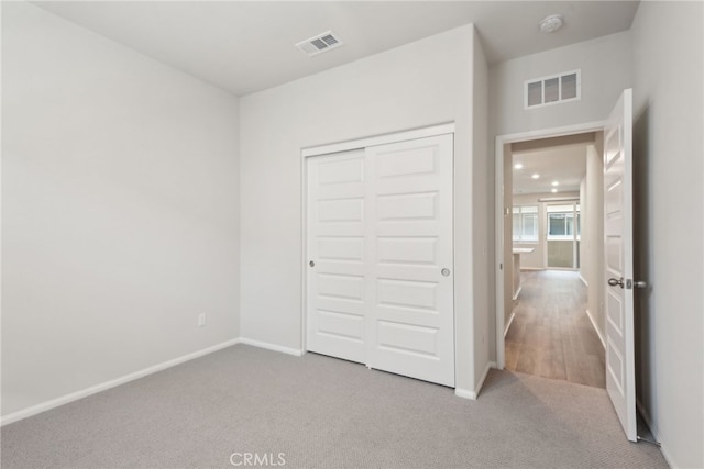 unfurnished bedroom with light colored carpet, a closet, and visible vents